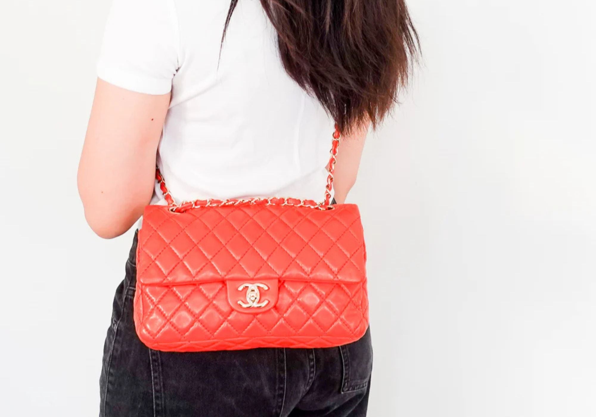 Chanel bag worn by a model, colour of the bag is red with silver CC logo flat bag