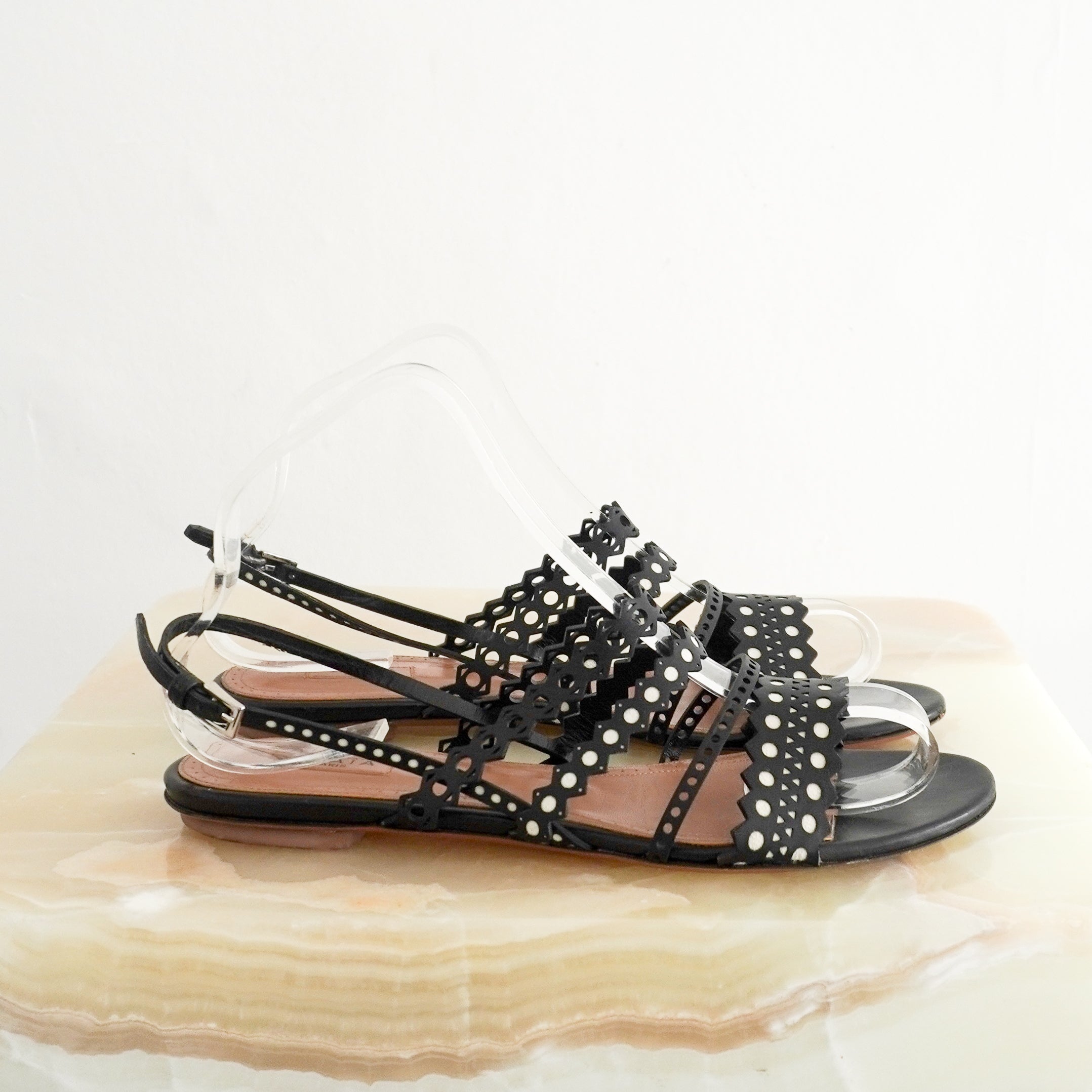 ALAÏA Laser-Cut Leather Flat Sandals in Black side photo chelsea london