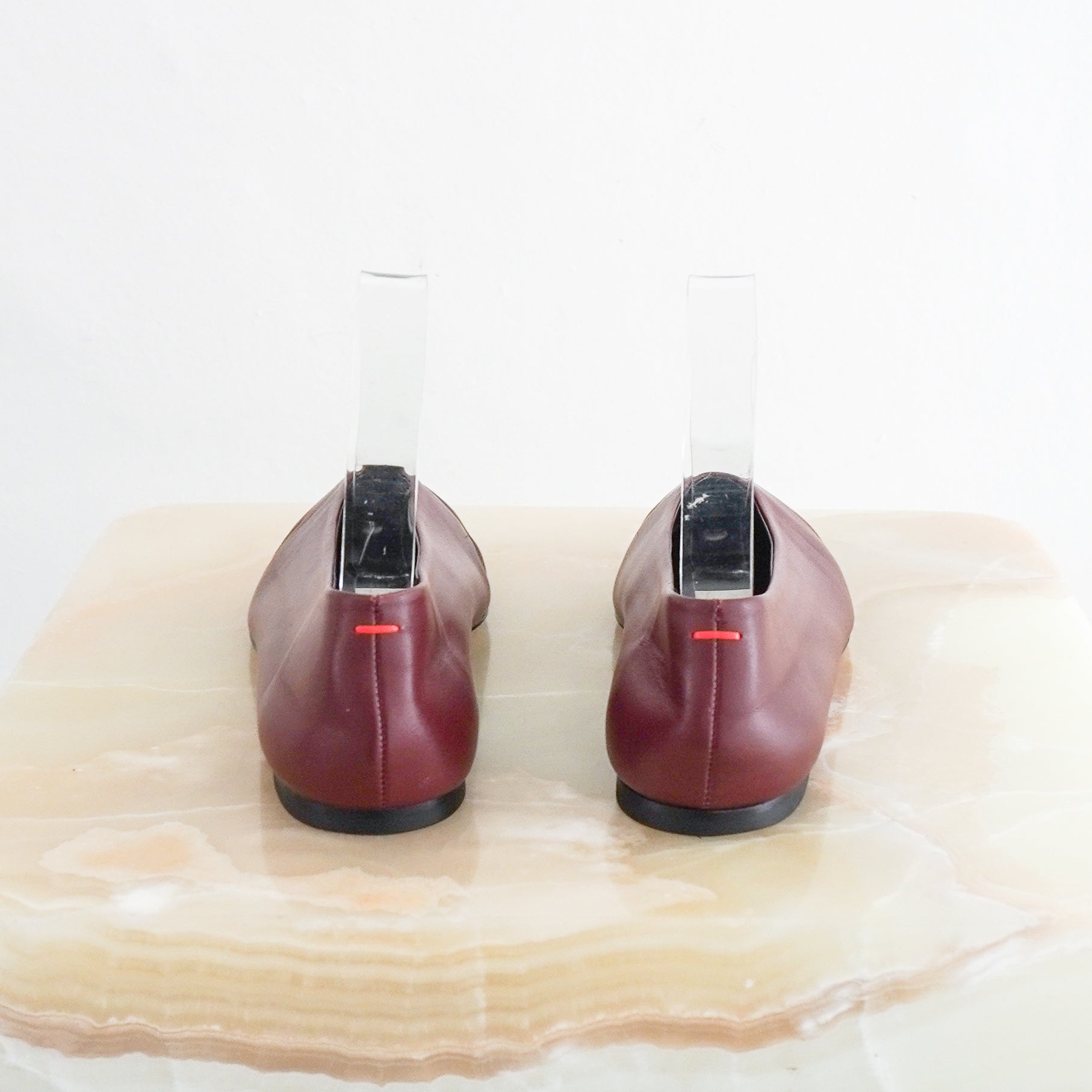 back view photo of a single Aeyde Burgundy Betty Ballet Flat, showcasing its smooth matte leather upper, high glove-like vamp, and tapered soft square toe