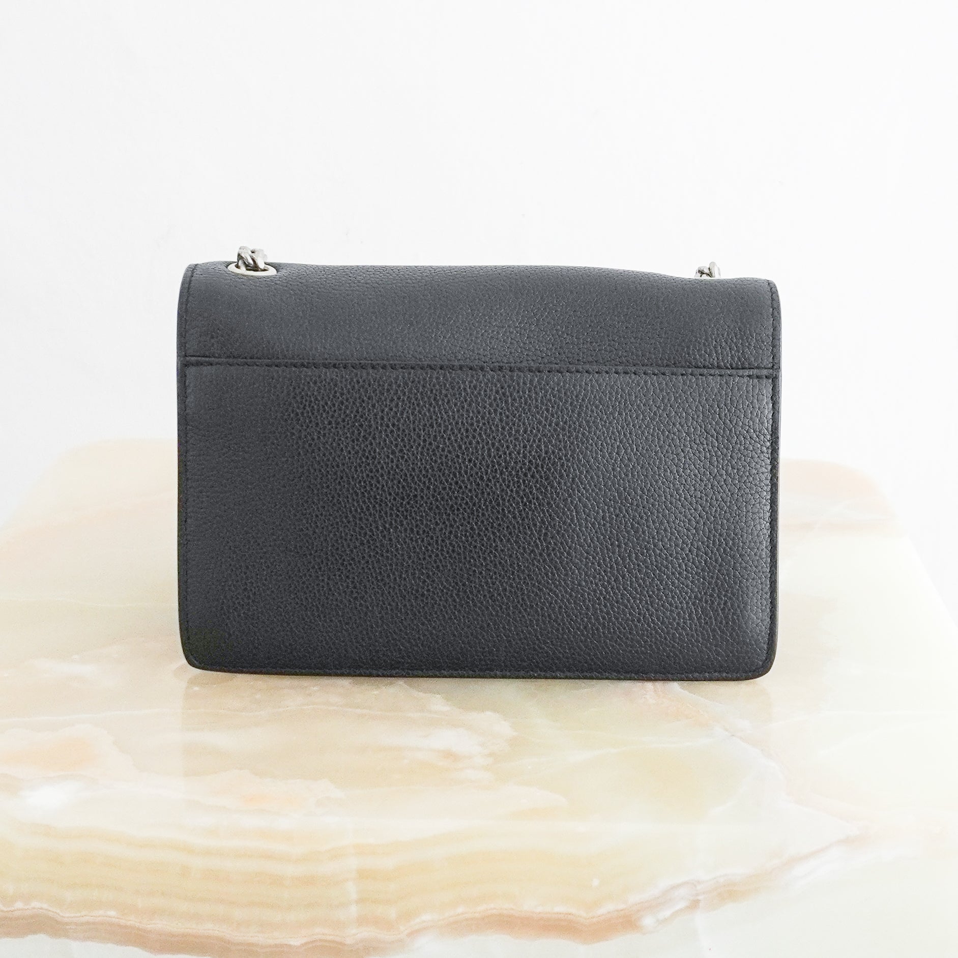 Back photo of a Small Kate Chain Bag crafted from luxurious black grained calfskin leather, this sophisticated crossbody combines clean architectural lines with the iconic silver-tone YSL Cassandre logo