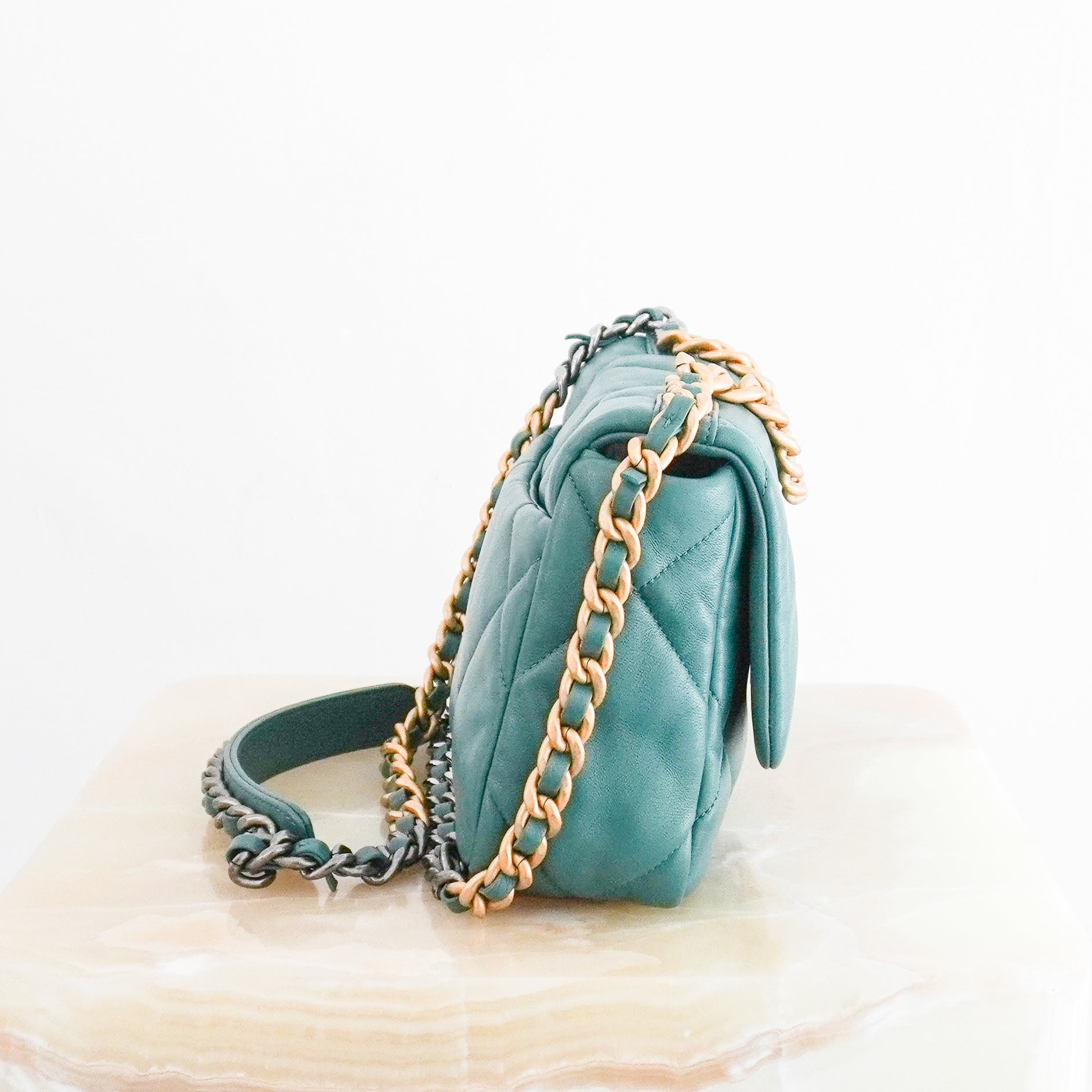 Side photo of a Chanel 19 Small Flap Bag crafted from supple aged calfskin leather with the collection's signature oversized diamond quilting.