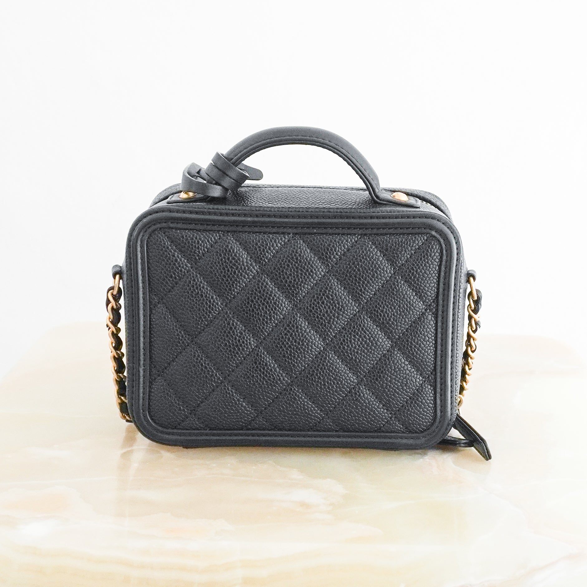 Back photo of a Chanel Vanity Case Crossbody Bag, crafted from luxurious black quilted caviar leather and finished with elegant champagne gold-tone hardware.