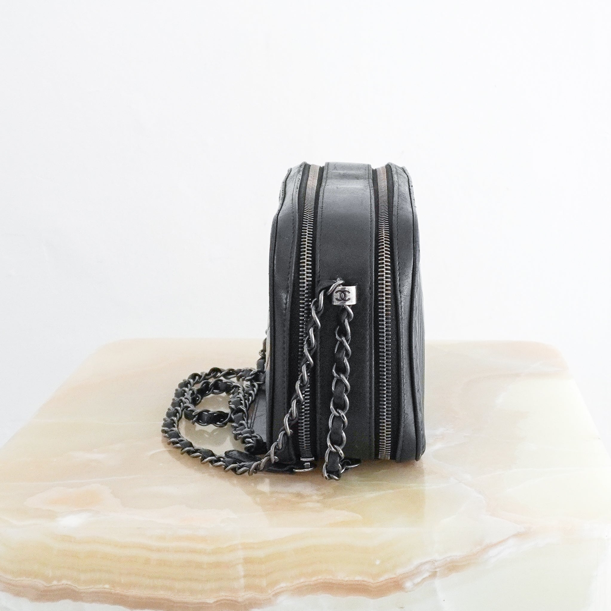 Side photo of a Chanel Cruise 2015 black lambskin camera bag with mixed quilted patterns and chain crossbody strap.