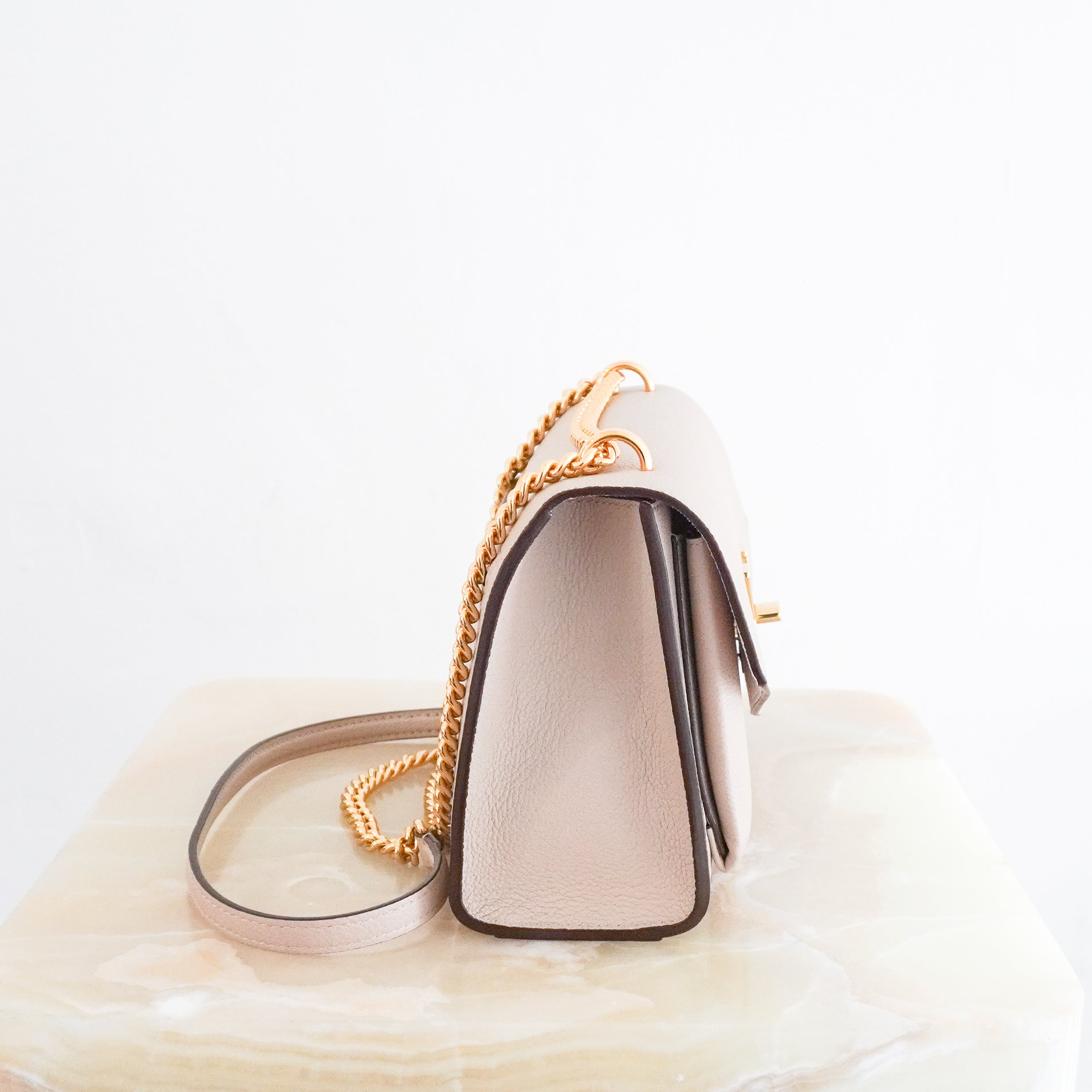 Louis Vuitton Lockme Chain Bag in greige grained calfskin leather featuring gold-tone hardware, the iconic LV turn-lock closure, exterior zipped pocket and leather-threaded chain strap