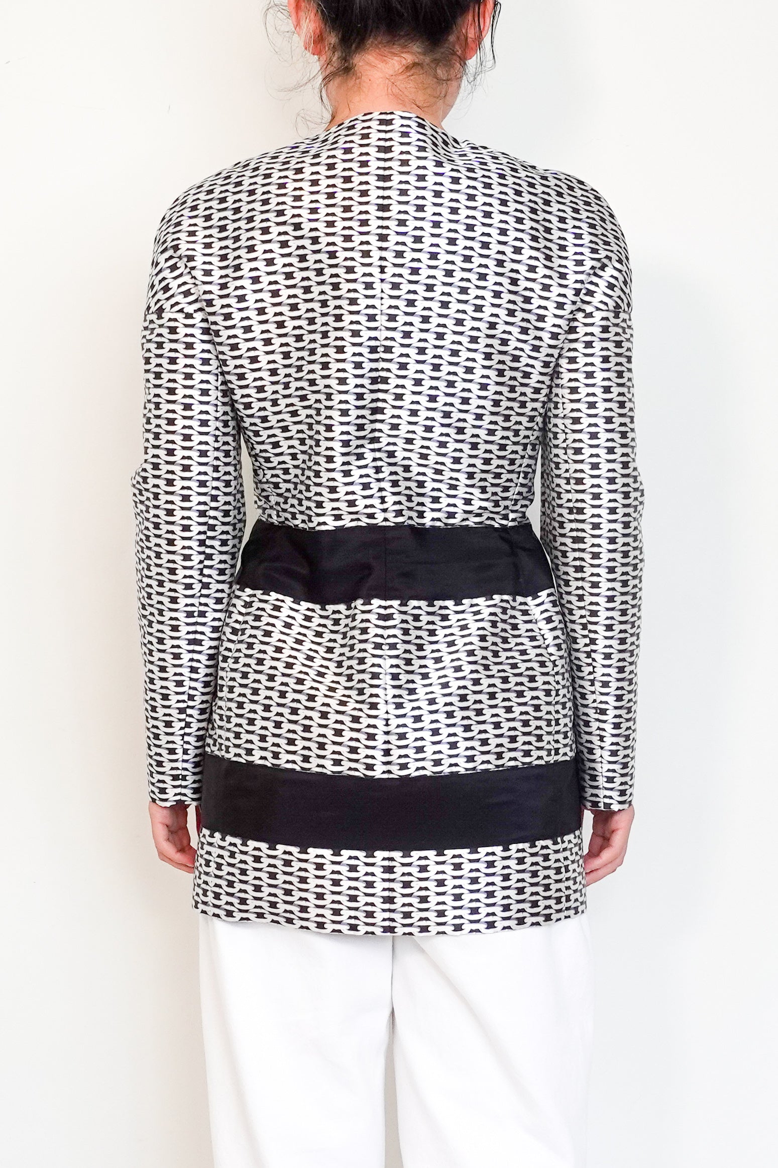 Person wearing a black and white patterned top with a black belt on a white background