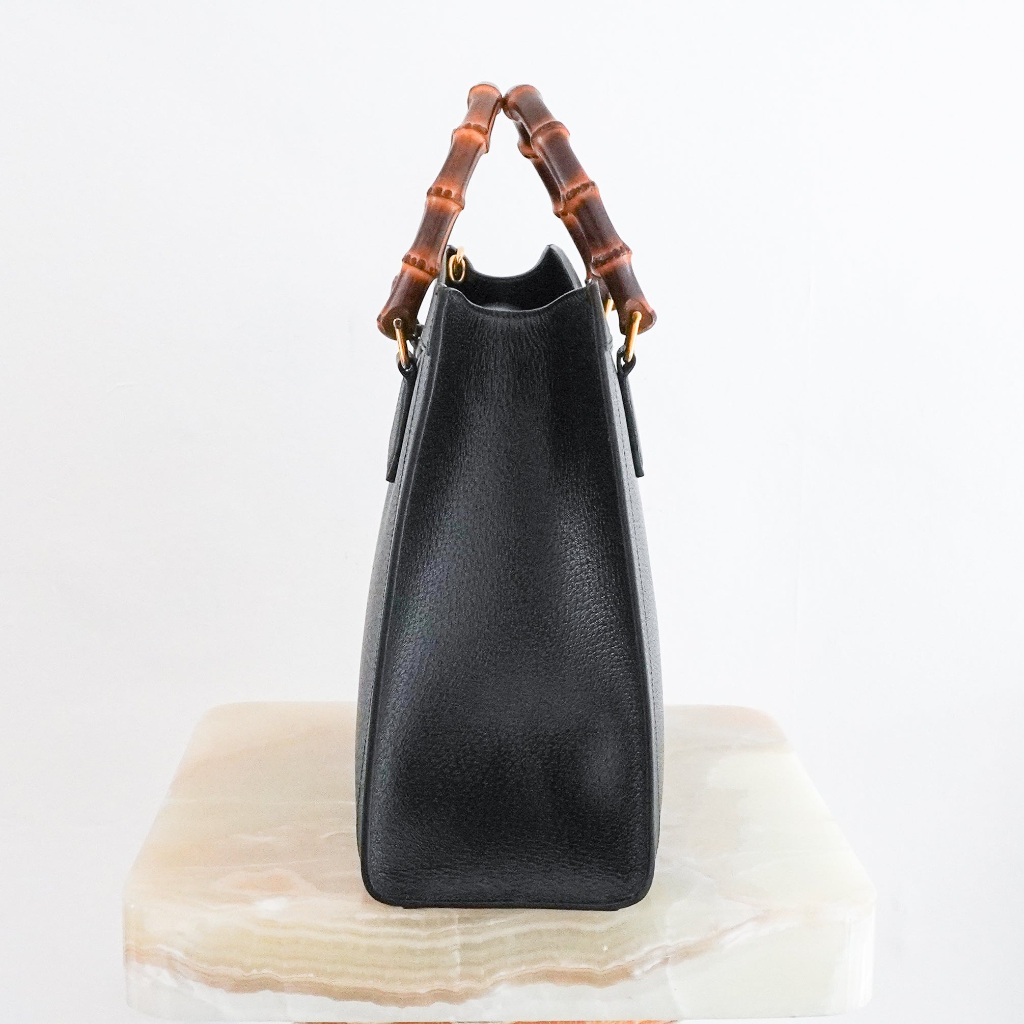 Side profile of the black Gucci Diana Medium Tote showing the slim gusset and structured leather shape.
