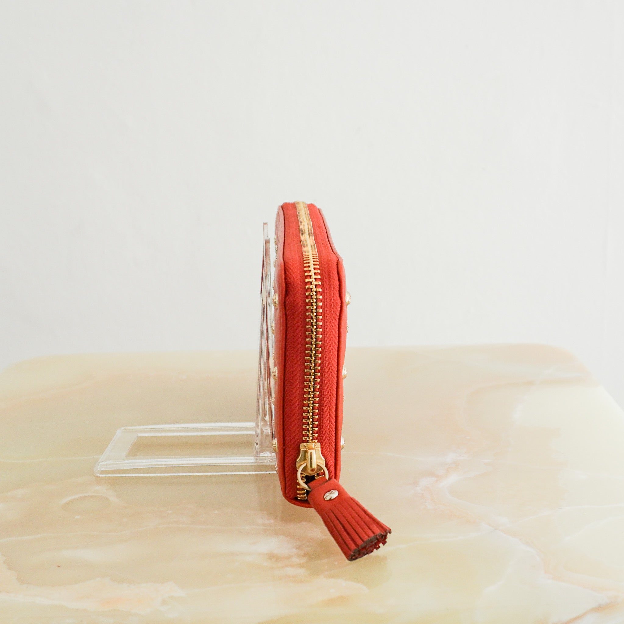 Side image of the Anya Hindmarch Studded Leather Zip Around Wallet in Orange