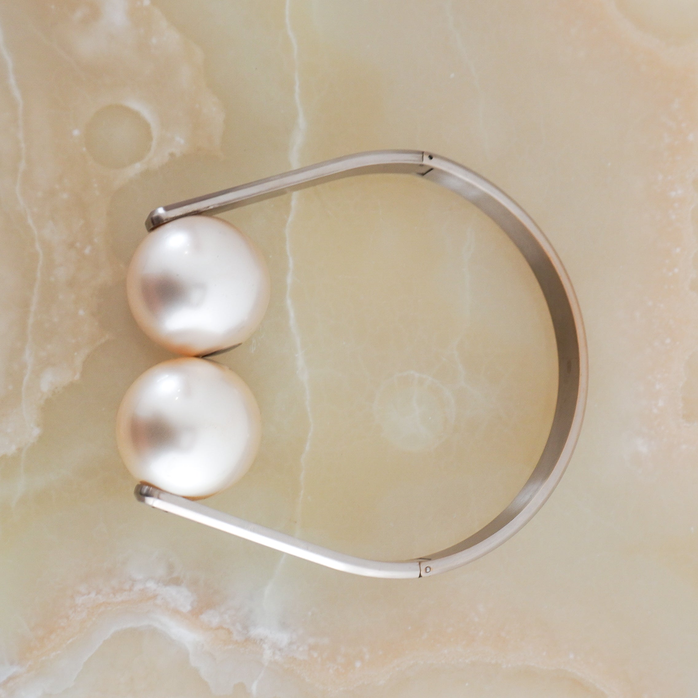 Side arial picture of the Chanel Spring/summer 2014 pearl choker, showing the pearls and arms.