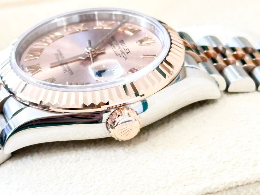 A close-up of a Rolex Datejust with a rose gold fluted bezel and pink Roman dial, highlighting the crown and Jubilee bracelet during authentication at Reloved Again