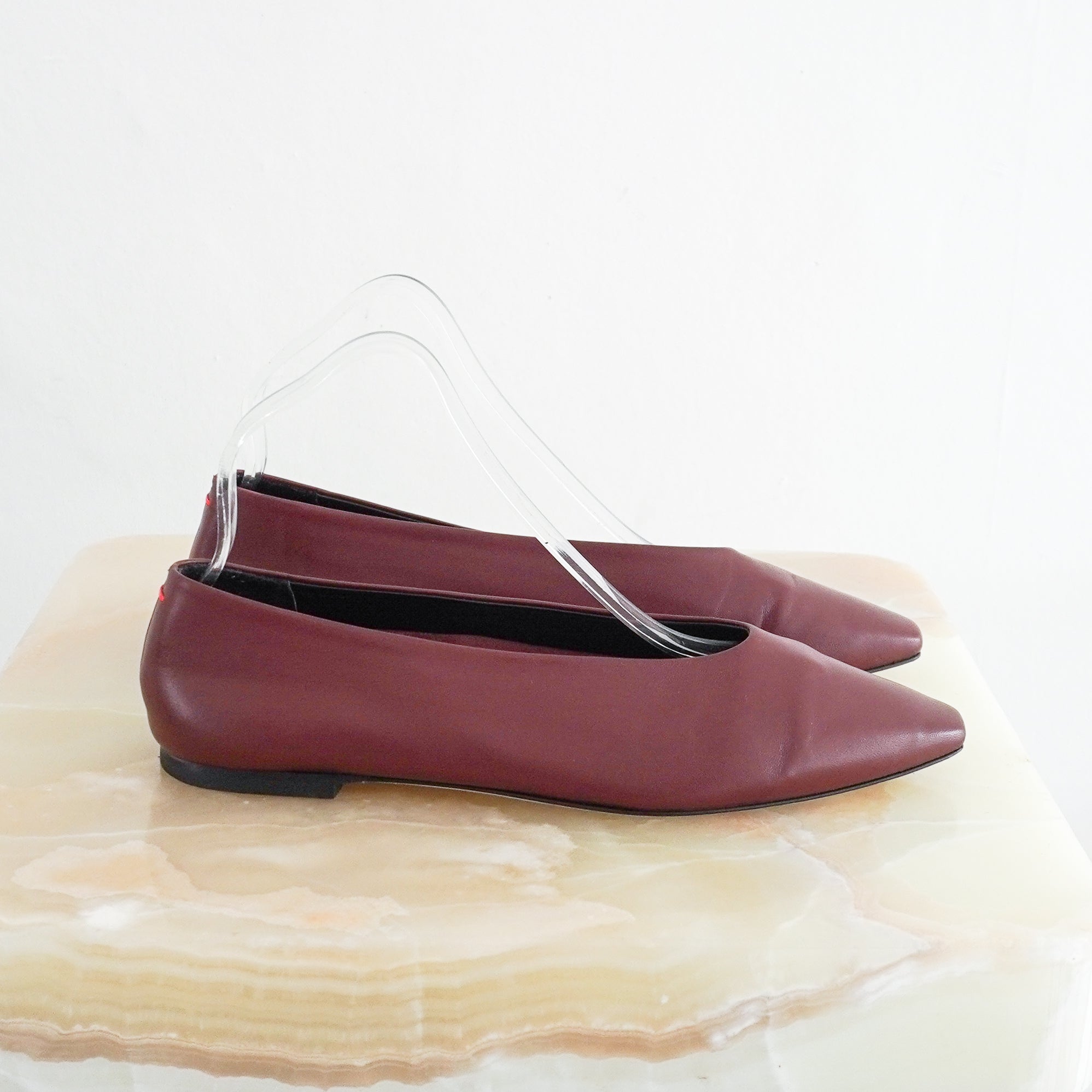 side view photo of a single Aeyde Burgundy Betty Ballet Flat, showcasing its smooth matte leather upper, high glove-like vamp, and tapered soft square toe