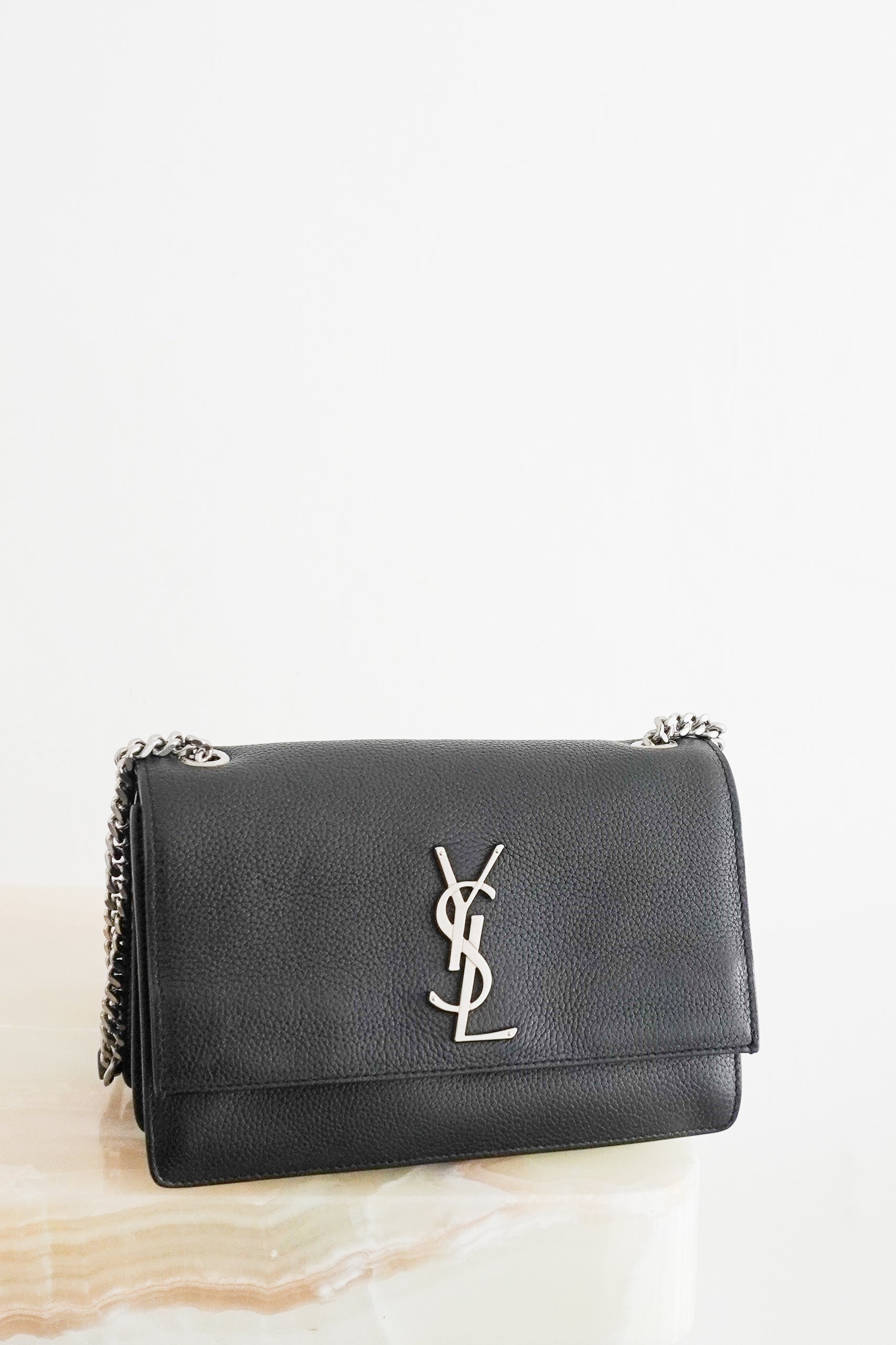 Front photo of a Small Kate Chain Bag crafted from luxurious black grained calfskin leather, this sophisticated crossbody combines clean architectural lines with the iconic silver-tone YSL Cassandre logo