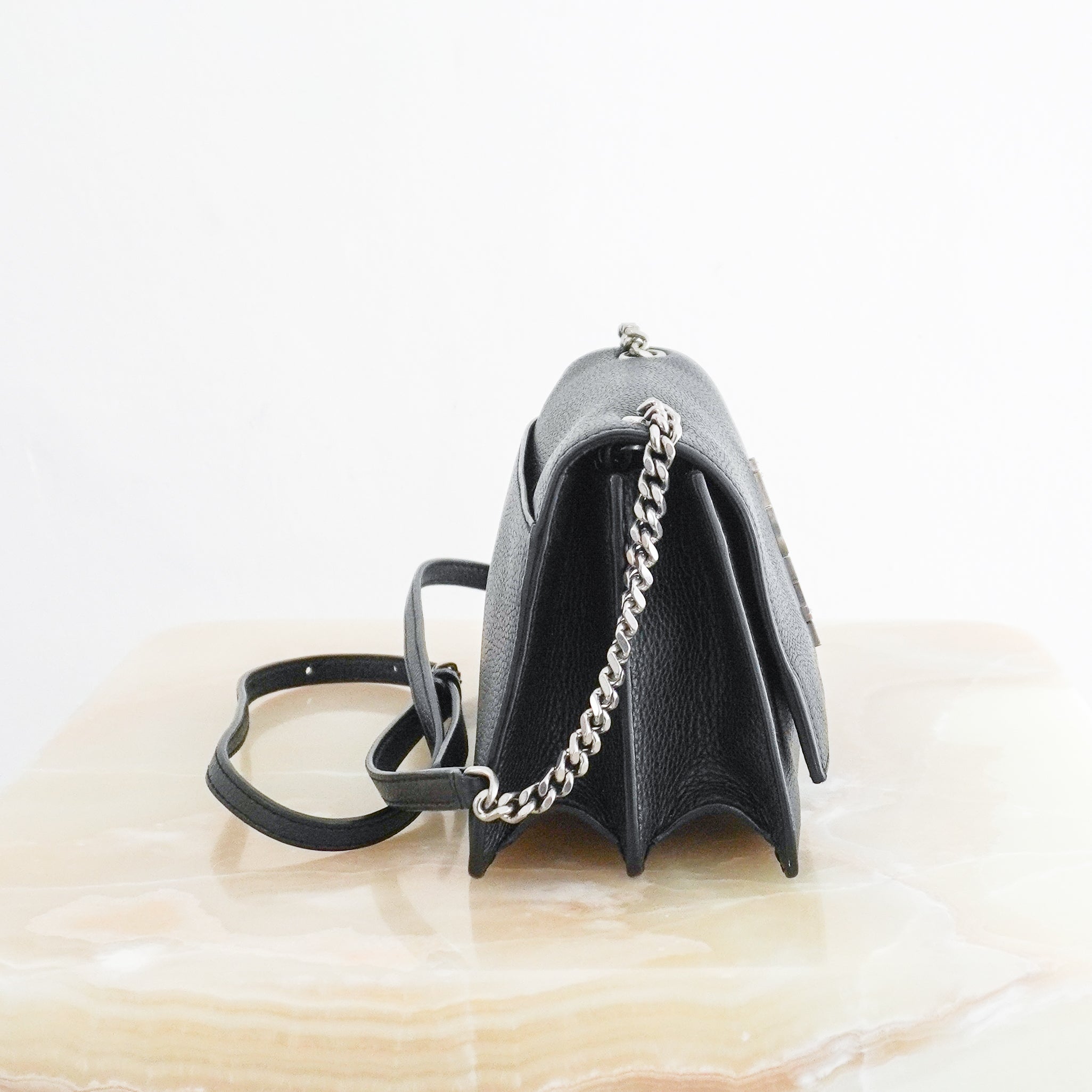 Side photo of a Small Kate Chain Bag crafted from luxurious black grained calfskin leather, this sophisticated crossbody combines clean architectural lines with the iconic silver-tone YSL Cassandre logo