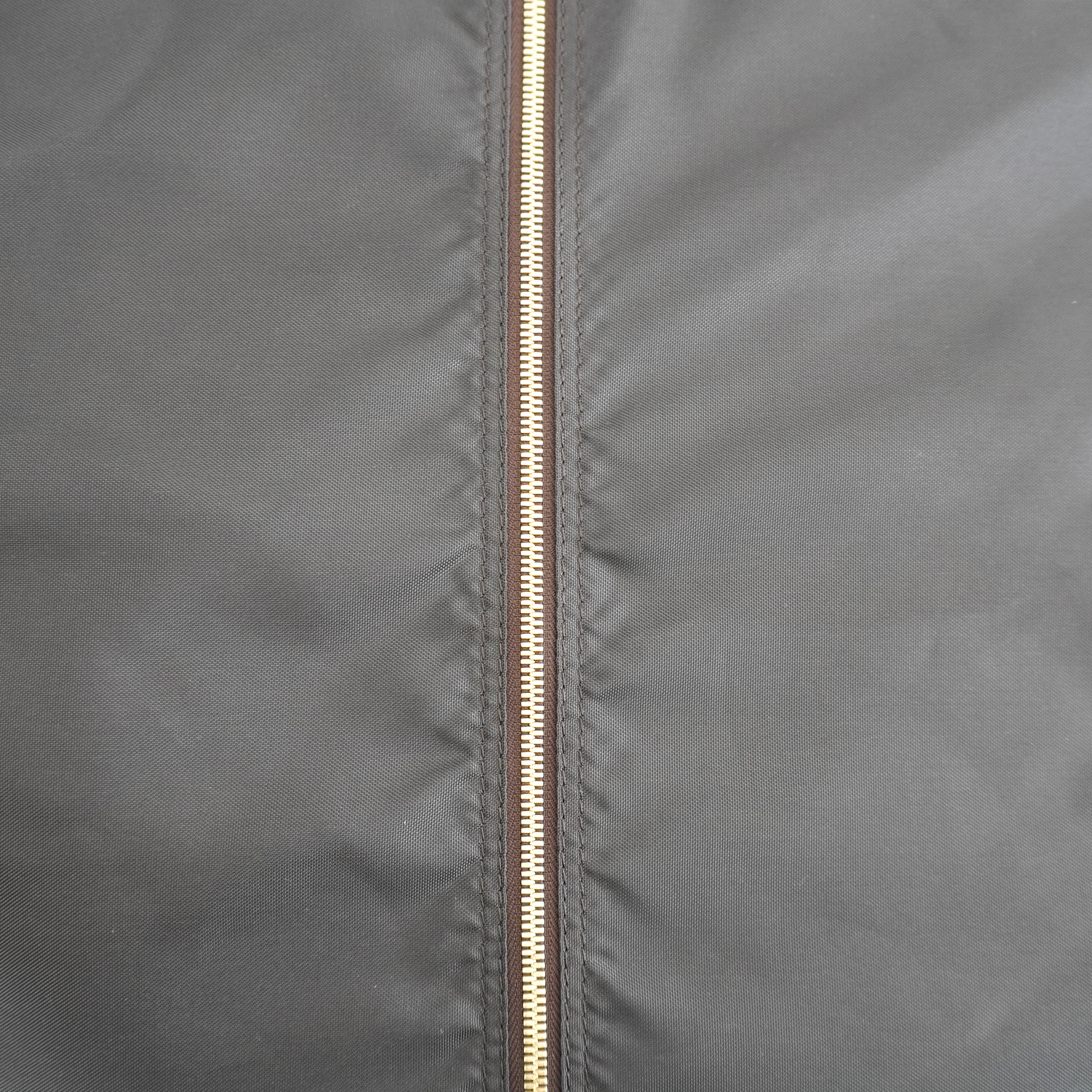 Close-up of a dark gray fabric jacket with a central gold-toned zipper.