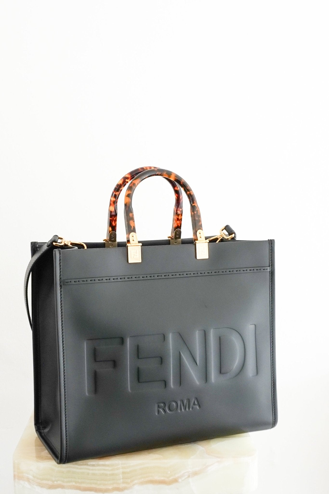 Black Fendi Roma tote bag with embossed logo detailing, gold-tone hardware and tortoiseshell-effect top handles.