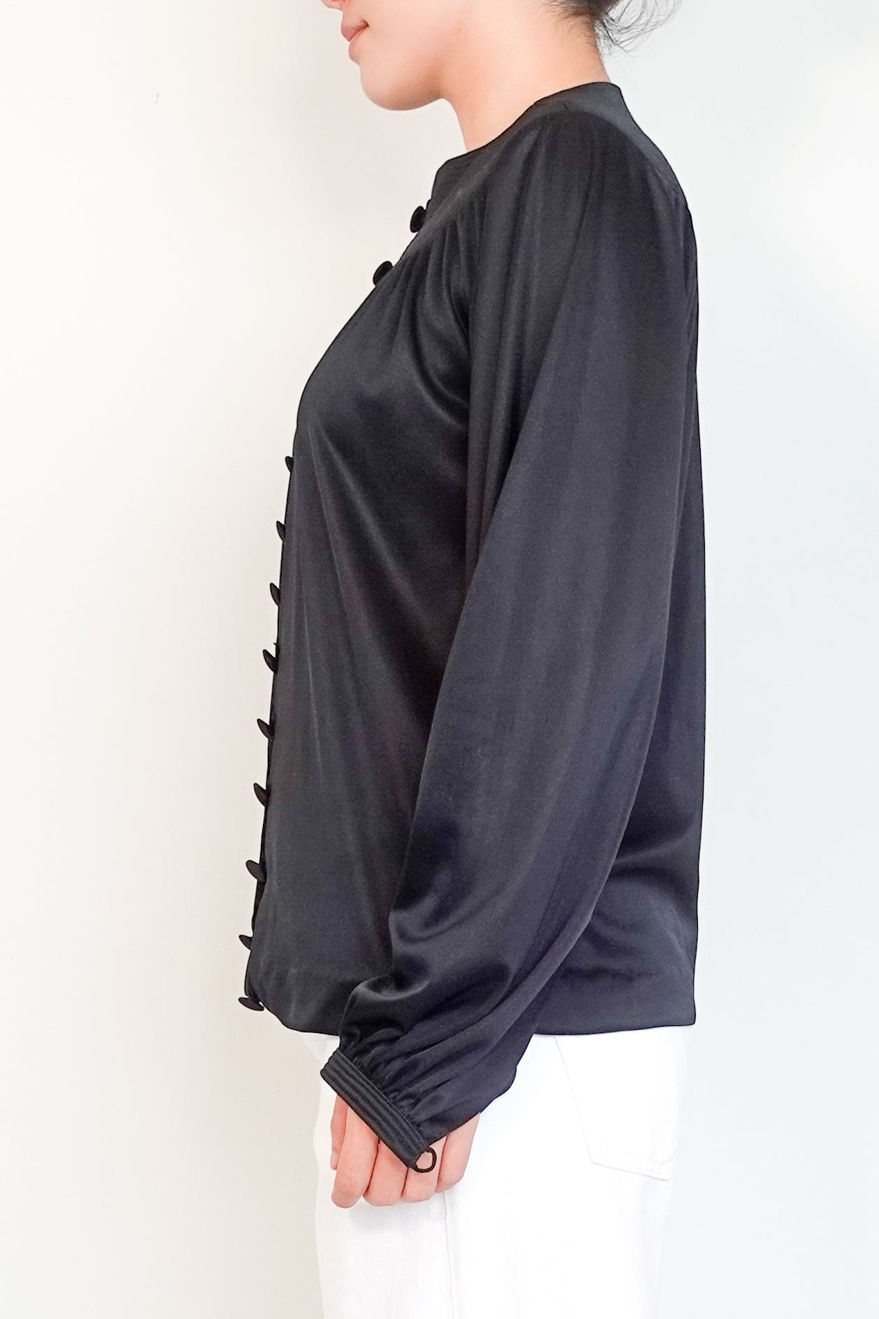 Black long-sleeve top with button details on a white background