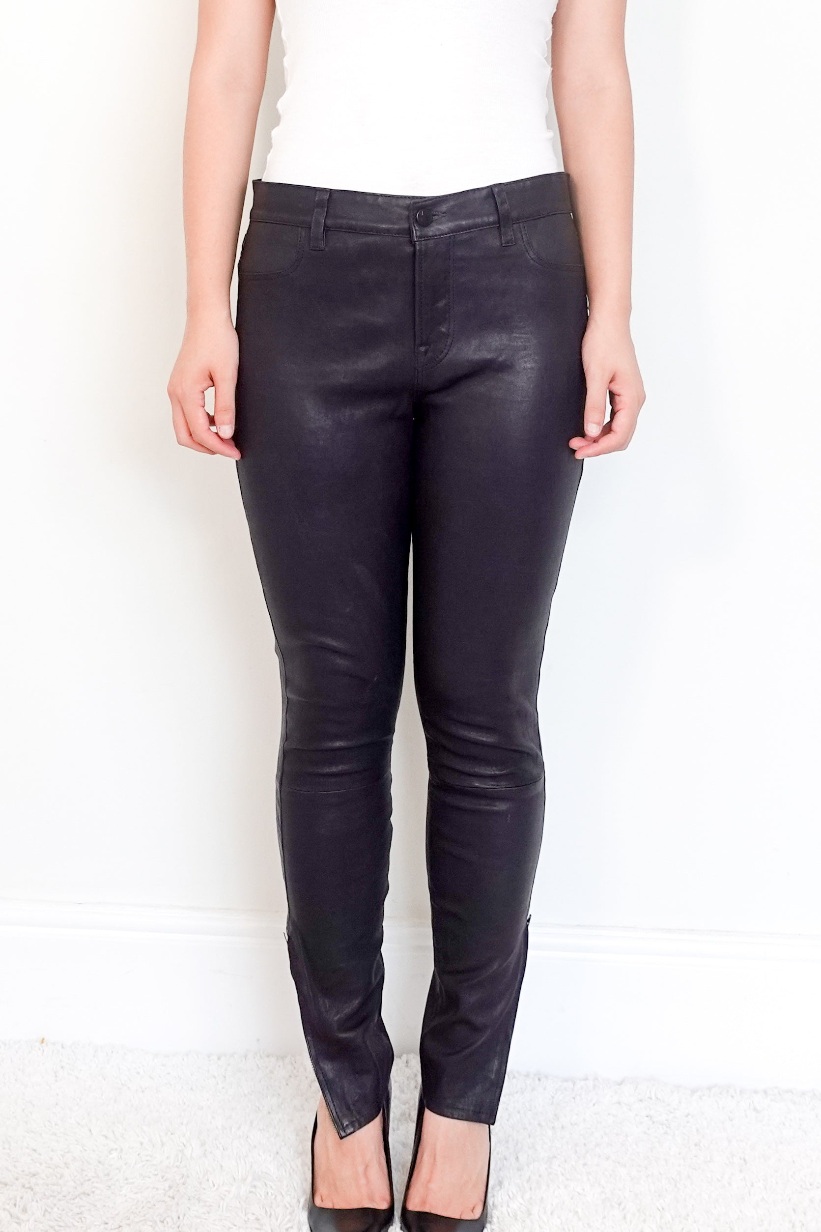 Black leather pants worn by a person on a white background
