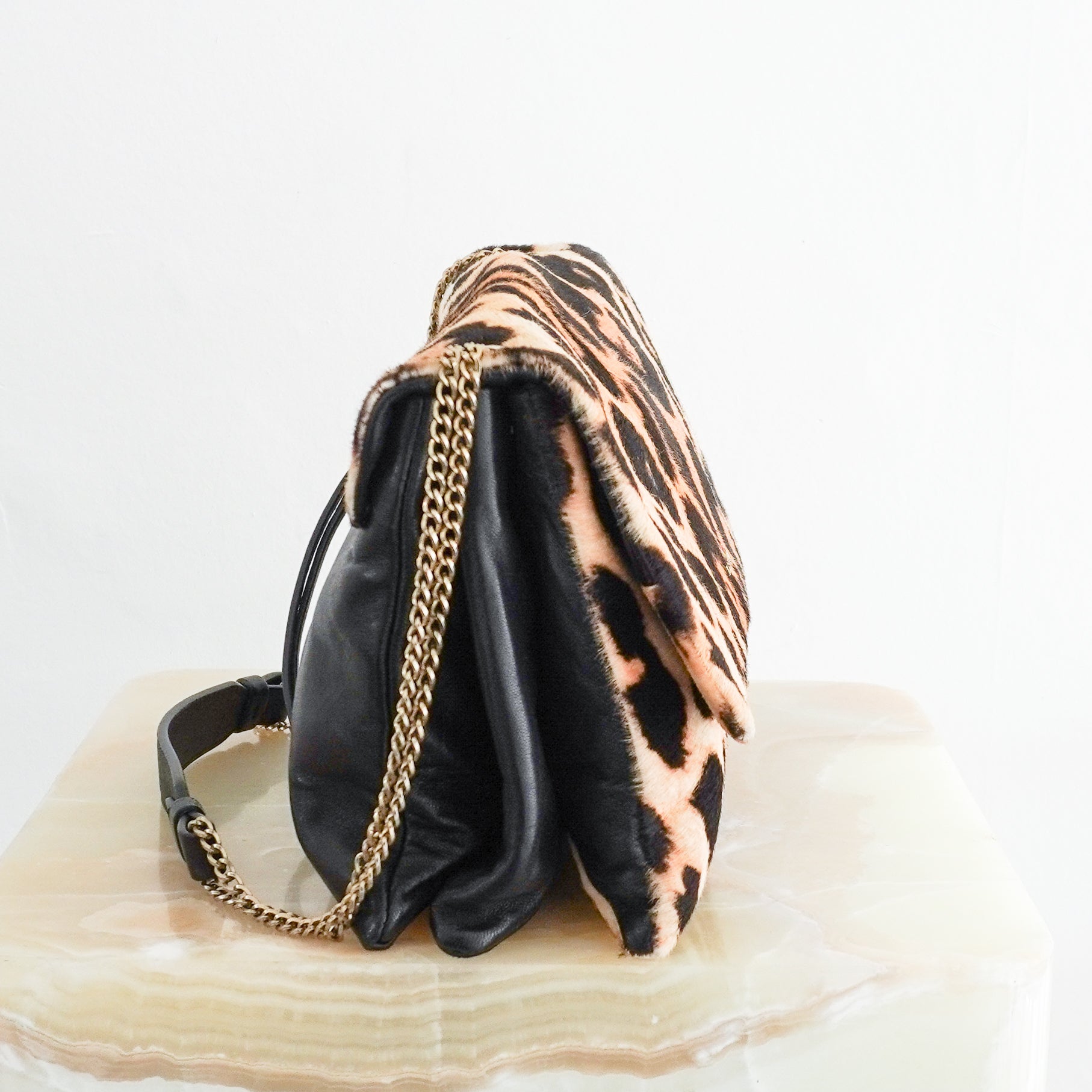 Side view photo of a Lanvin Leopard Print Pony Hair & Leather Bag, showcasing its bold leopard pattern flap and delicate gold-tone chain strap