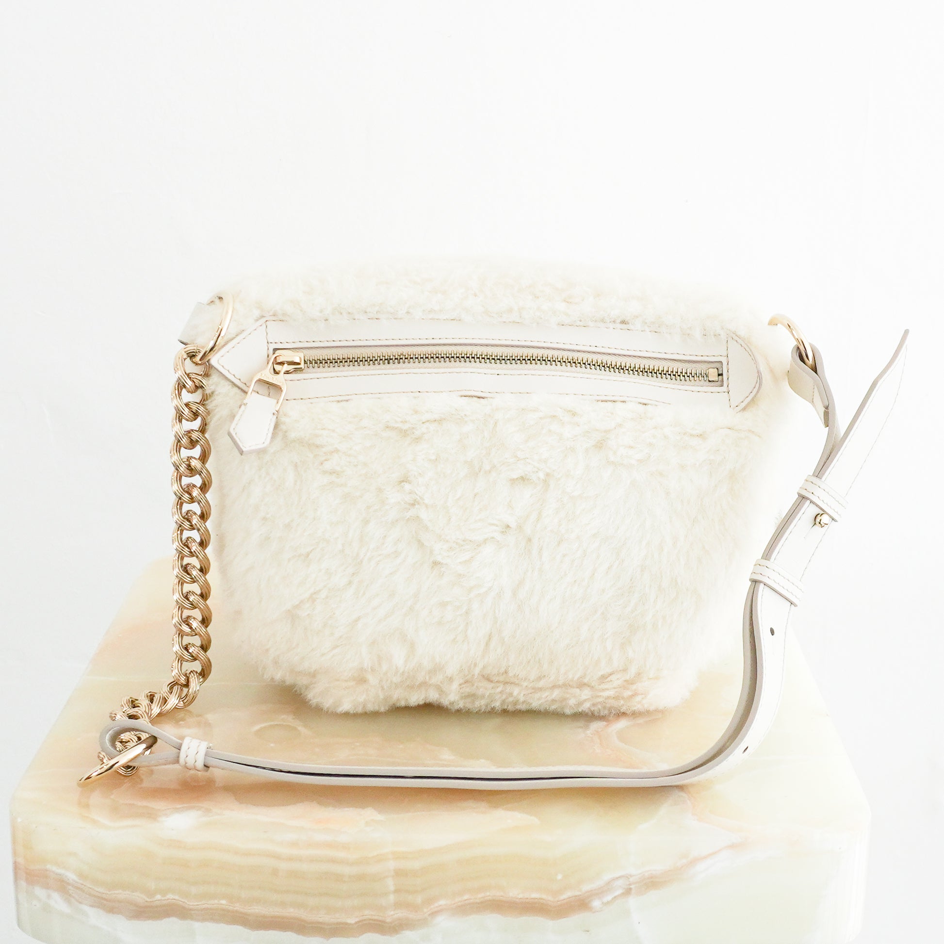Back view photo of a MaxMara White Camelux Teddy Fur Shoulder Bag, featuring a plush textured exterior, gold-toned zipper hardware, and an attached leather strap