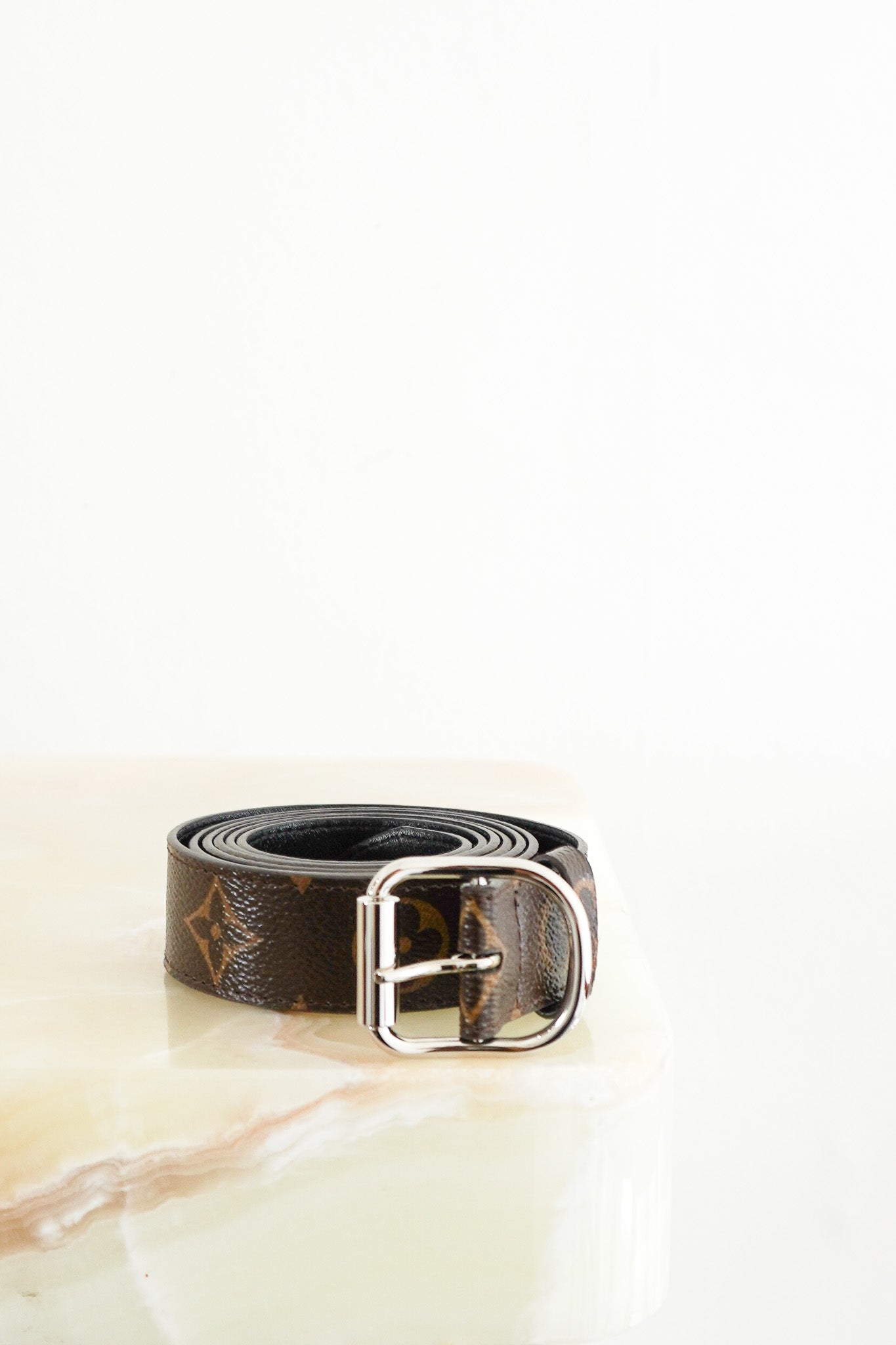Front photo of a Louis Vuitton Brown Monogram Canvas Belt, featuring the iconic brown monogram coated canvas rolled into a coil with a silver-tone horseshoe-shaped pin buckle.